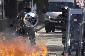 Ein Molotow-Cocktail geht vor Polizisten in Flammen auf.