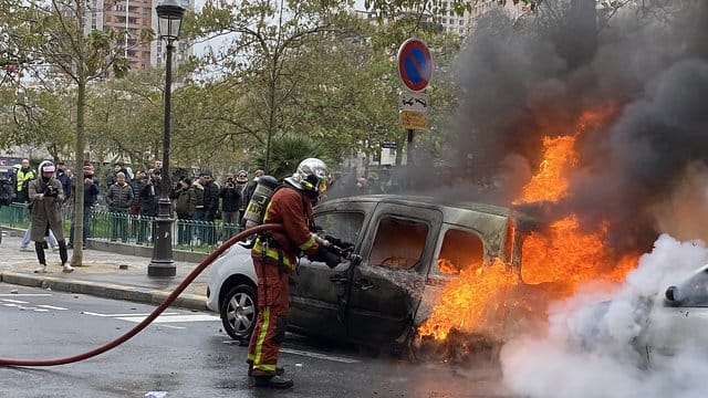 Ein Feuerwehrmann löscht in Paris ein von "Gelbwesten" in Brand gesetztes Auto.