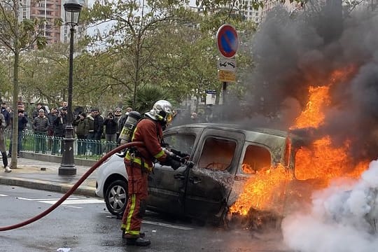 Ein Feuerwehrmann löscht in Paris ein von "Gelbwesten" in Brand gesetztes Auto.