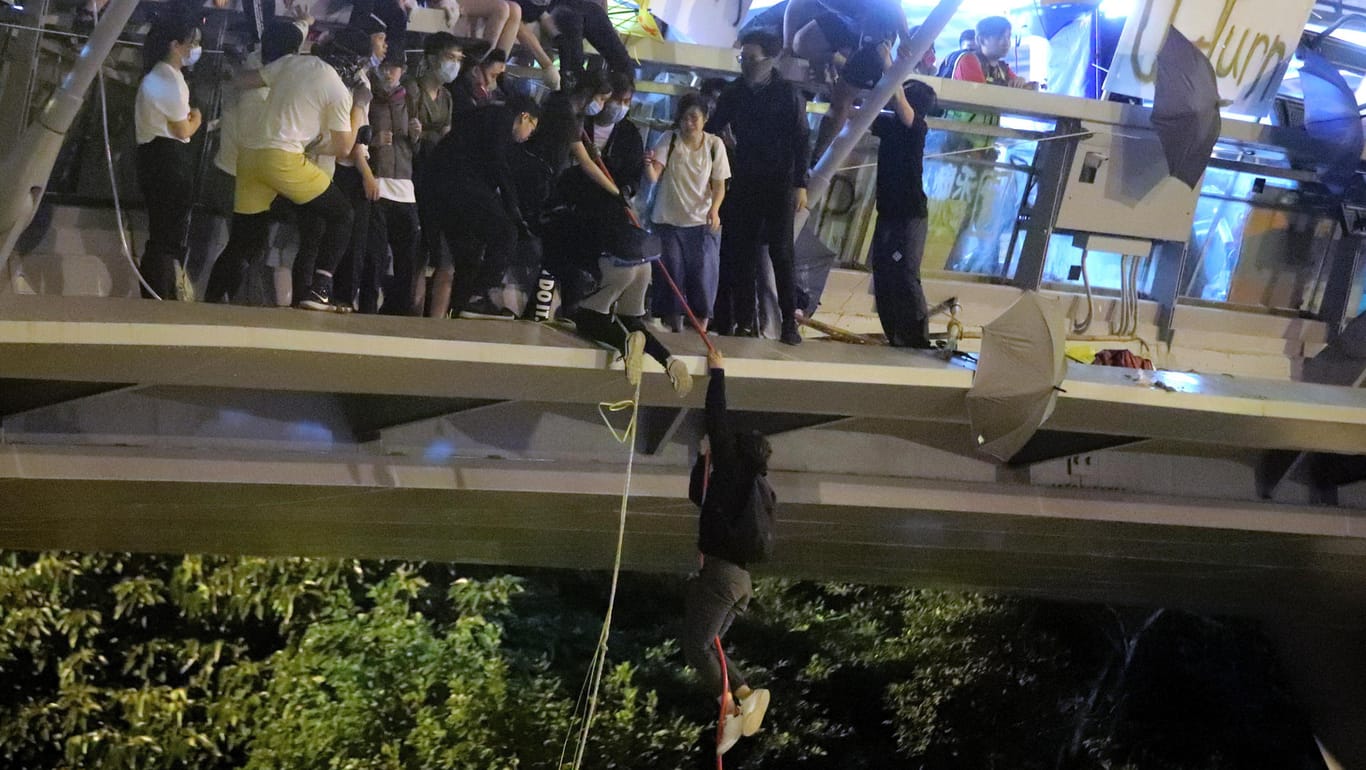 Flucht vom Uni-Campus: Ein Protestierer seilt sich von einer Fußgängerbrücke auf eine Autobahn hinab.