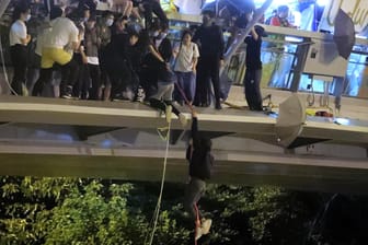 Flucht vom Uni-Campus: Ein Protestierer seilt sich von einer Fußgängerbrücke auf eine Autobahn hinab.