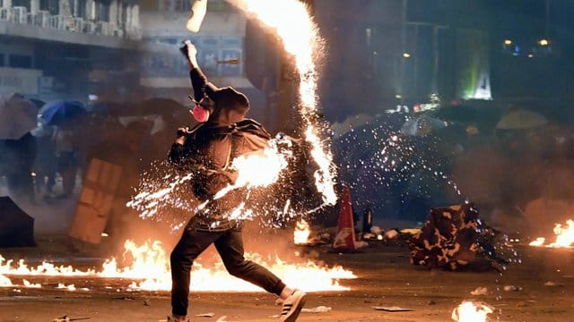 Ein Demonstrant wirft einen Molotowcocktail auf die Polizei.