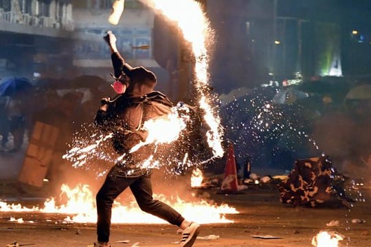 Ein Demonstrant wirft einen Molotowcocktail auf die Polizei.