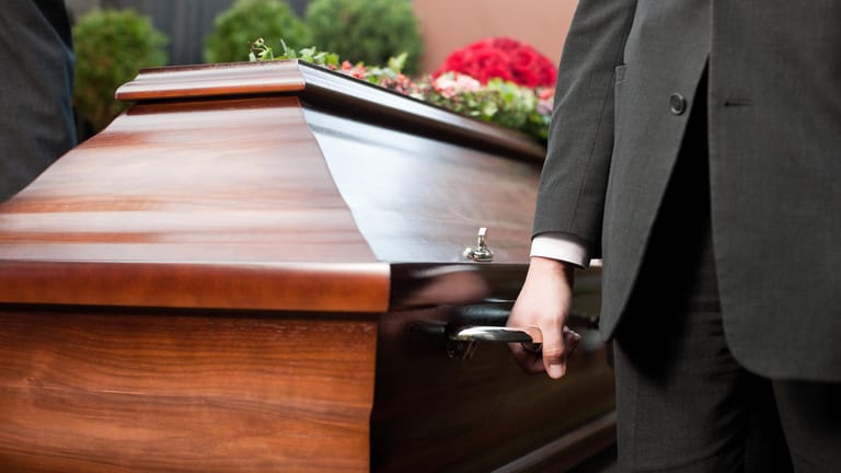 Männer tragen einen Sarg: Die Kosten für eine Beerdigung hängen unter anderem davon ab, ob eine Erd- oder Feuerbestattung erfolgt.