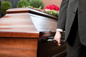 Männer tragen einen Sarg: Die Kosten für eine Beerdigung hängen unter anderem davon ab, ob eine Erd- oder Feuerbestattung erfolgt.