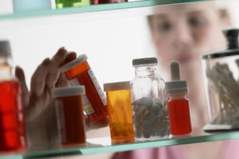 Eine Frau nimmt ein Medikament aus der Hausapotheke: Mittel gegen Schmerzen sollte jeder für den Notfall zu Hause haben.