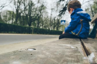 Ein trauriger Junge sitzt auf einer Bank: Wenn Empfänger von Hartz IV gegen Auflagen verstoßen, kann das eine Sanktionierung zur Folge haben. Die trifft auch Kinder.