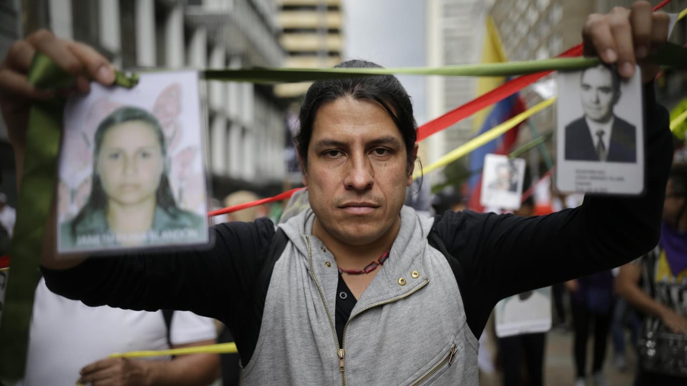 Ein Demonstrant hält Bilder vermisster Menschen hoch: Studenten, Bauern und Arbeiter marschierten am Donnerstag von verschiedenen Punkten zum Zentrum der Hauptstadt Kolumbiens.