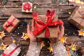 Eine Frau hält ein Weihnachtsgeschenk in den Händen: Welche Gadgets eignen sich zum Verschenken?