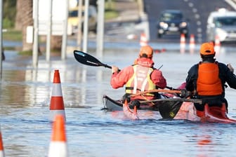 Zwei Männer paddeln mit ihren Kajaks durch die überflutete Straße in Palavas-les-Flots nach einem nächtlichen Sturm in Südfrankreich.