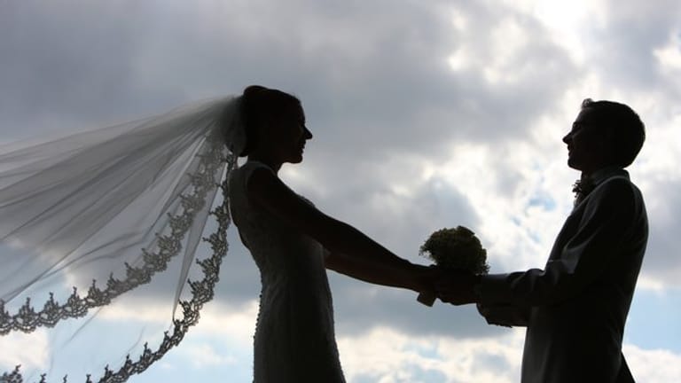 Die Silhouette eines frisch vermählten Hochzeitspaares zeichnet sich im Gegenlicht ab.
