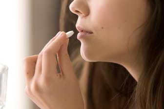 Eine Frau nimmt eine Tabletten ein: Schmerzmittel können bei der akuten Behandlung von Migräne helfen.