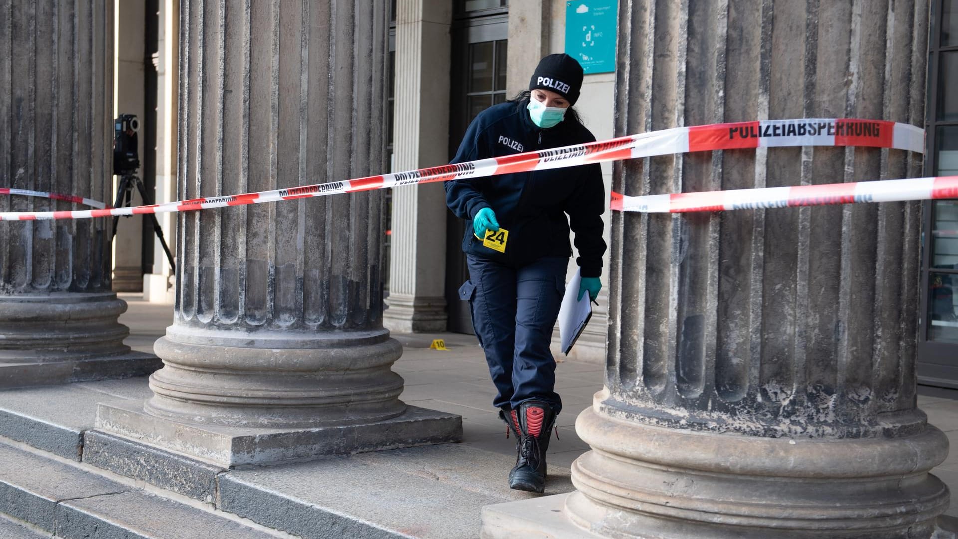 Eine Polizistin geht vor dem Gebäude der Schinkelwache hinter einem Absperrband entlang.
