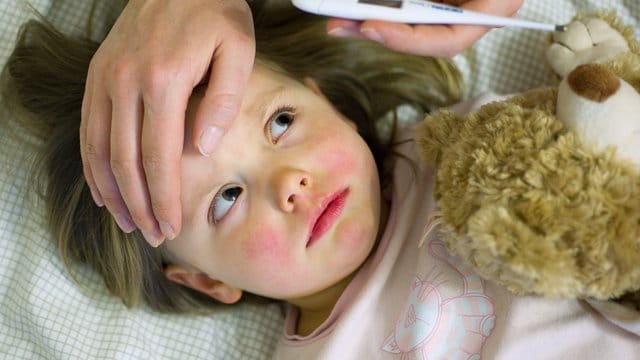 Bei einem kranken Kind wird das Fieber gemessen (Symbolbild): Aktuell leiden besonders viele Kinder in München unter dem RS-Virus.