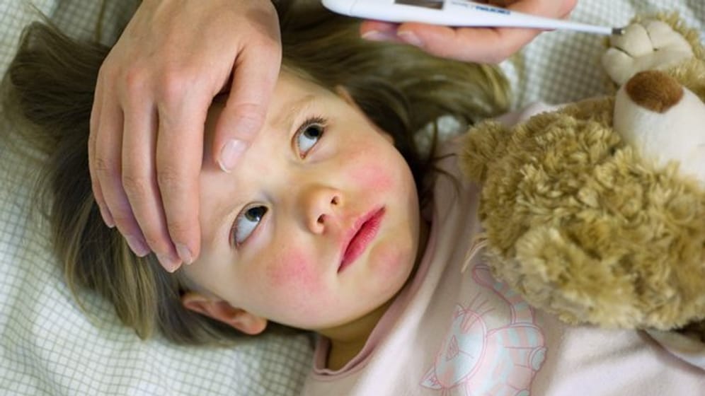 Bei einem kranken Kind wird das Fieber gemessen (Symbolbild): Aktuell leiden besonders viele Kinder in München unter dem RS-Virus.