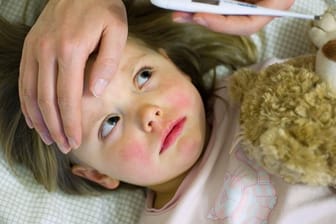 Bei einem kranken Kind wird das Fieber gemessen (Symbolbild): Aktuell leiden besonders viele Kinder in München unter dem RS-Virus.
