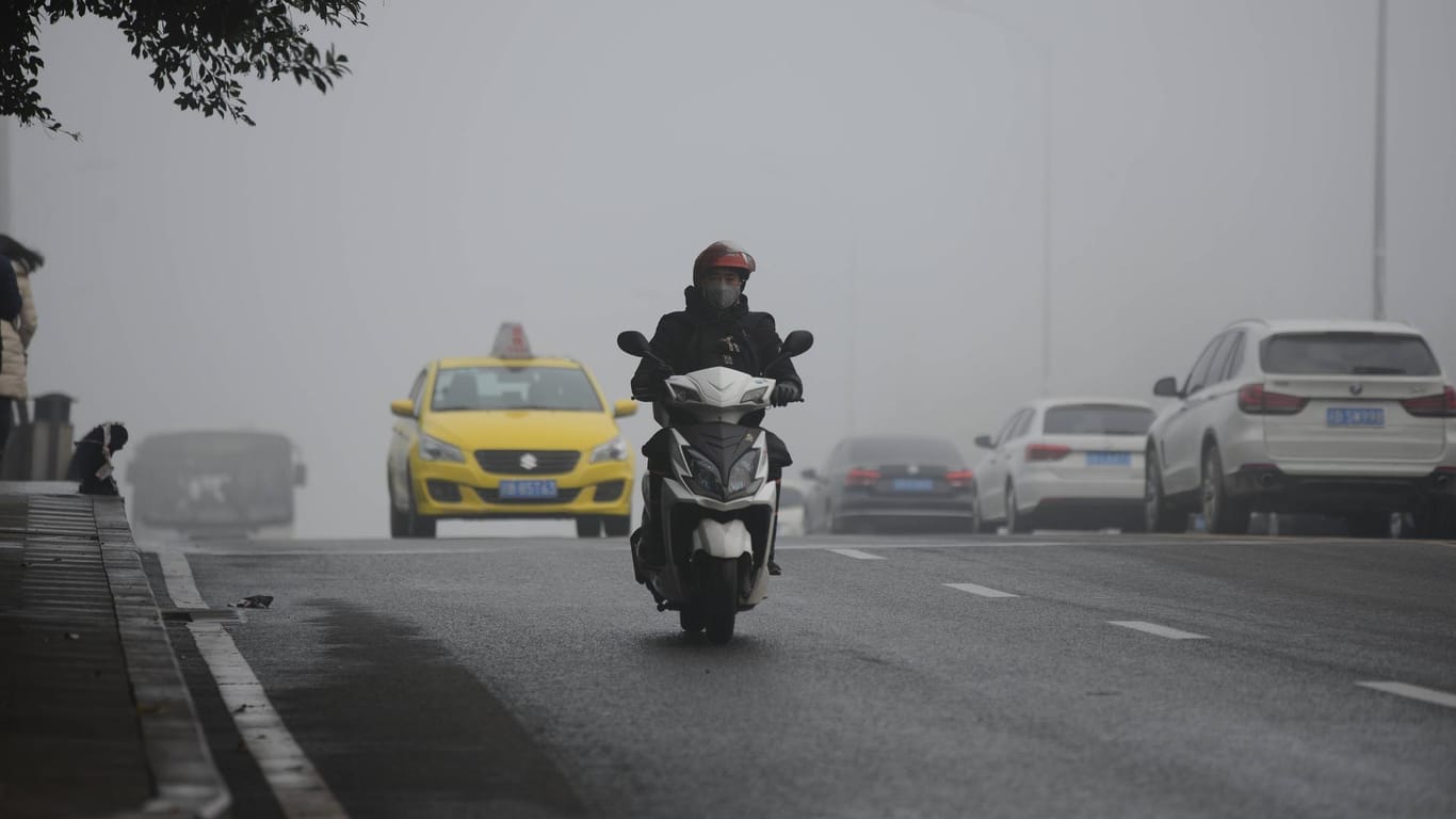 Ein Moped-Fahrer mit Atemschutz in China: In China werden besonders viele Treibhausgase produziert.
