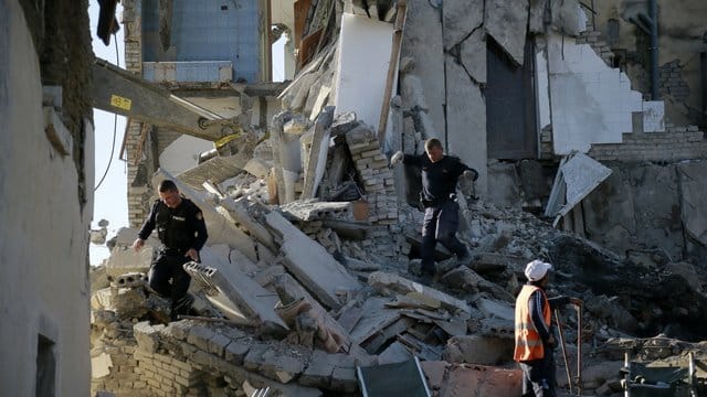 Nach einem Erdbeben durchsuchen Rettungskräfte ein zerstörtes Gebäude.