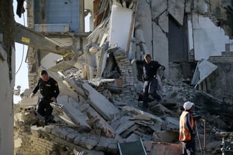 Nach einem Erdbeben durchsuchen Rettungskräfte ein zerstörtes Gebäude.
