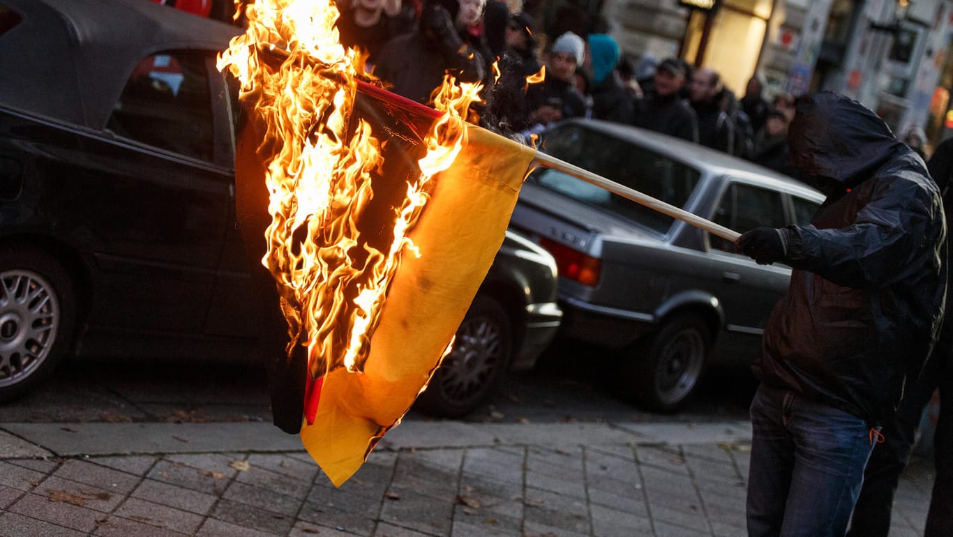 Demonstration in Hamburg: Ein Teilnehmer einer Kundgebung verbrennt eine deutsche Flagge.