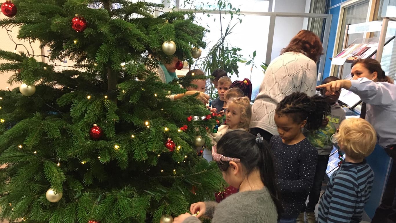 Kinder schmücken einen Weihnachtsbaum: Mit etwas Hilfe fanden die Schmückstücke den richtigen Platz am Tannenbaum auf der Polizeiwache.