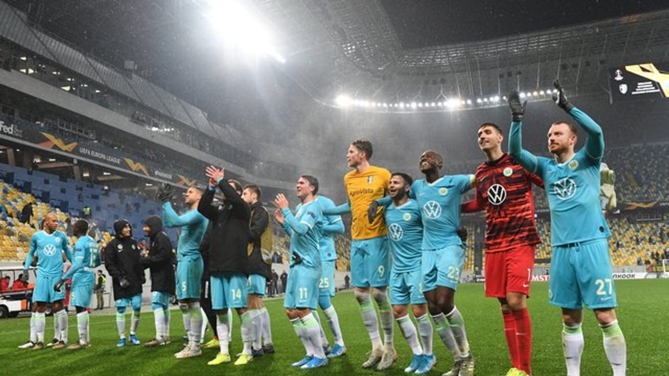 Die Wolfsburger Spieler feiern nach Abpfiff mit den Fans den Sieg.