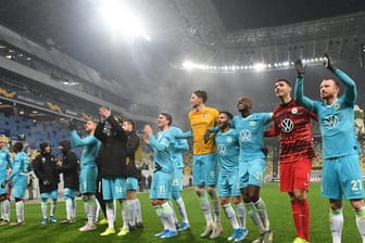 Die Wolfsburger Spieler feiern nach Abpfiff mit den Fans den Sieg.