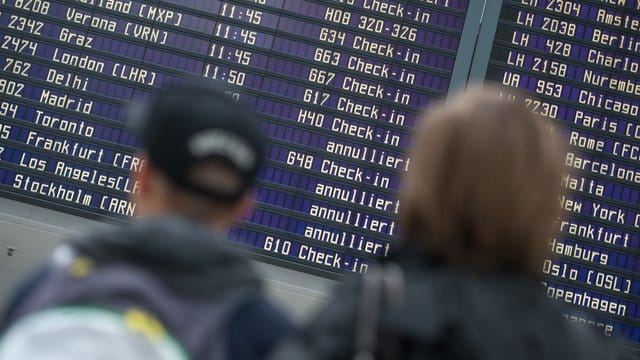 Reisende stehen vor einer Abflugtafel im Flughafen in München. Reisende stehen vor einer Abflugtafel im Flughafen in München.