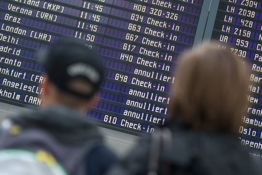 Reisende stehen vor einer Abflugtafel im Flughafen in München. Reisende stehen vor einer Abflugtafel im Flughafen in München.
