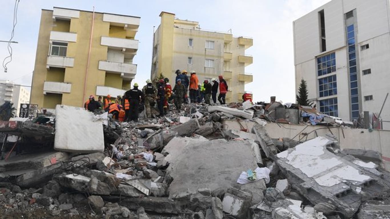 Rettungskräfte stehen auf den Trümmern eines eingestürzten Gebäudes.