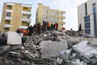 Rettungskräfte stehen auf den Trümmern eines eingestürzten Gebäudes.