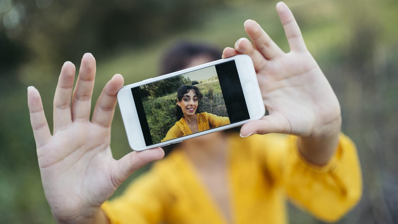 Junge Frau fotografiert sich mit dem Handy: Welche Kamera ist in diesem Jahr die beste?