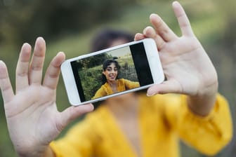 Junge Frau fotografiert sich mit dem Handy: Welche Kamera ist in diesem Jahr die beste?