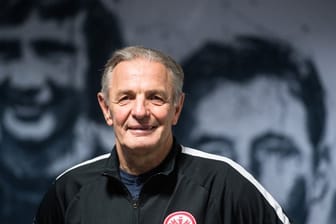 Karl-Heinz "Charly" Körbel steht vor einer Wand mit den Porträts ehemaliger Eintrachtspieler.