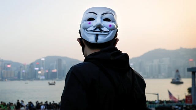 Ein prodemokratischer Demonstrant mit Guy-Fawkes-Maske beobachtet eine Kundgebung in Hongkong. Ein prodemokratischer Demonstrant mit Guy-Fawkes-Maske beobachtet eine Kundgebung in Hongkong.