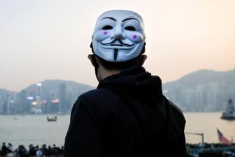 Ein prodemokratischer Demonstrant mit Guy-Fawkes-Maske beobachtet eine Kundgebung in Hongkong.