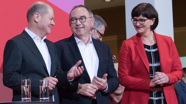 Norbert Walter-Borjans (M) und Saskia Esken freuen sich nach der Bekanntgabe des Ergebnisses der Abstimmung zum SPD-Vorsitz im Willy-Brandt-Haus neben Olaf Scholz. Walter-Borjans und Esken haben die Abstimmung gewonnen.