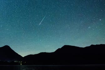 Eine Sternschnuppe leuchtet vor der Milchstraße am Himmel über dem Walchensee: Im Dezember gibt es einiges am Sternenhimmel zu sehen.