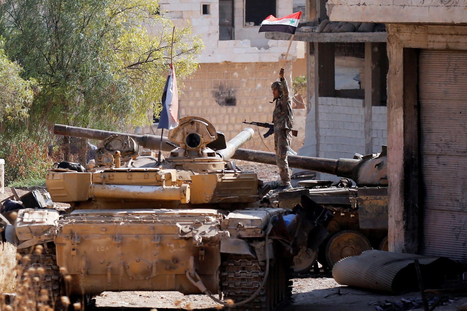 Ein Soldat steht in Idlib auf einem Panzer und hält eine syrische Flagge hoch: Regierungstruppen und verbündete Milizen gingen gegen Rebellen vor. (Archivbild)