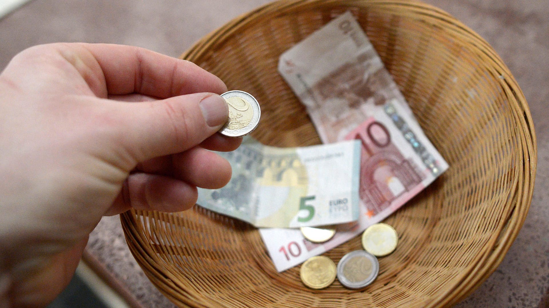 Jemand gibt Geld in einen Sammelkorb: Besonders viele Spenden kamen bei Katastrophen zusammen, die in den Medien groß präsentiert wurden. Jemand gibt Geld in einen Sammelkorb: Besonders viele Spenden kamen bei Katastrophen zusammen, die in den Medien groß präsentiert wurden.