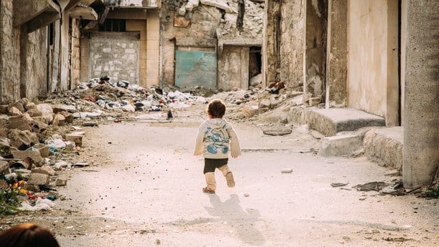 Ein kleiner Junge geht durch eine vom Bürgerkrieg zerstörte Straße in der syrischen Metropole Aleppo.