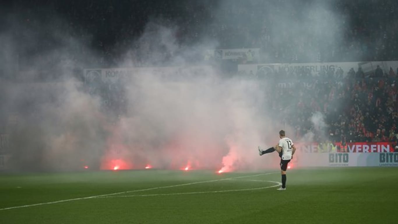 Dichte Rauchschwaden durchziehen das Mainzer Stadion, nachdem Feuerwerkskörper aus dem Gästeblock auf dem Rasen gelandet sind.