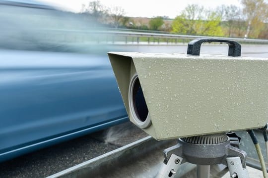 Ein blaues Auto fährt an einem Blitzer vorbei (Symbolbild): Am Freitag wird in Frankfurt und auf einigen Autobahnen geblitzt.