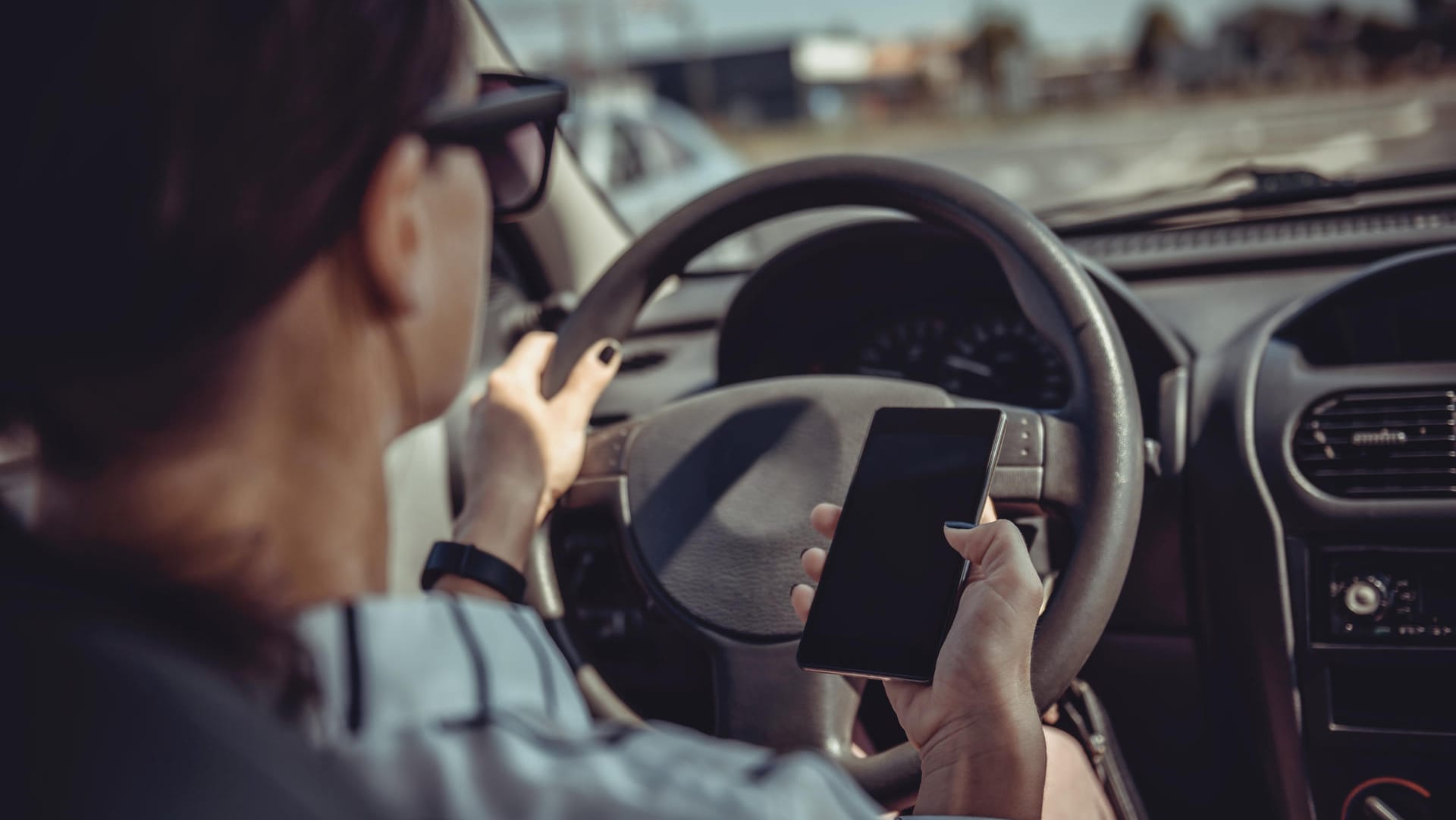 Eine Frau im Auto mit Handy in der Hand: Selbst am Steuer können viele Fahrer auf ihre elektronischen Geräte nicht verzichten. Eine Frau im Auto mit Handy in der Hand: Selbst am Steuer können viele Fahrer auf ihre elektronischen Geräte nicht verzichten.