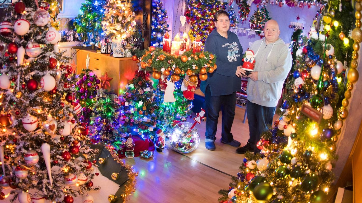 Susanne und Thomas Jeromin inmitten von Weihnachtsbäumen in ihrem Wohnzimmer: Schon im Sommer starteten die Vorbereitungen.