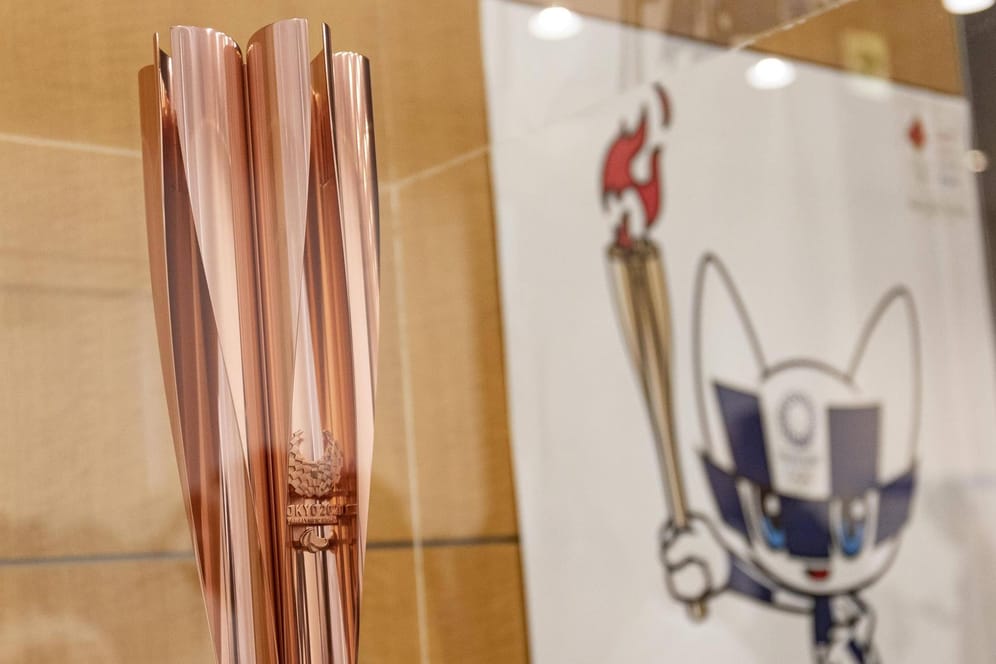 In ihr wird das Olympische Feuer nach Tokio gebracht: Die Olympische Fackel – im Hintergrund das Maskottchen der Spiele "Miraitowa".