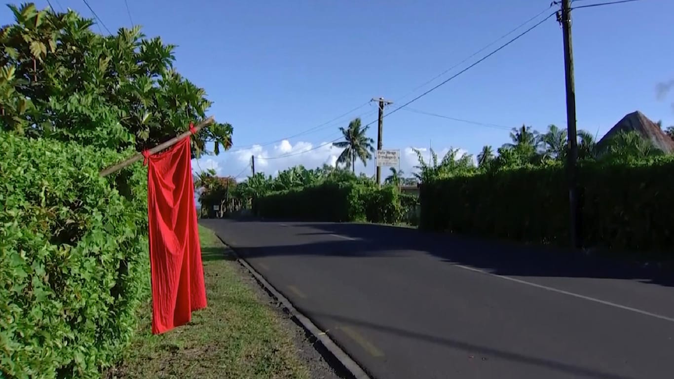 Eine rote Fahne an der Hecke eines Grundstücks in Samoa: Das Zeichen signalisiert, dass noch nicht alle Personen im Haushalt geimpft wurden.