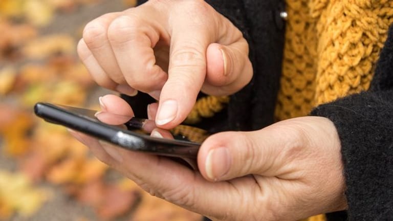 Frau tippt auf ein Smartphone (Symbolbild): Mit Links in einer SMS versuchen Betrüger, Nutzer in eine Falle zu locken.