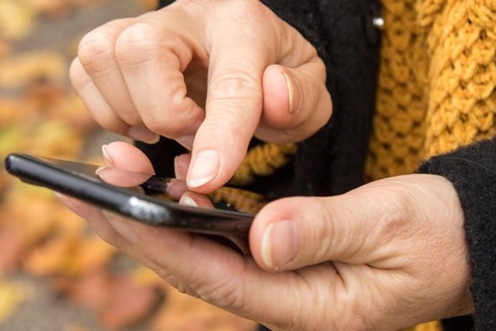 Frau tippt auf ein Smartphone (Symbolbild): Mit Links in einer SMS versuchen Betrüger, Nutzer in eine Falle zu locken.