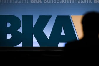 Auf einer Bundeskriminalamt-Tagung steht ein Mann vor dem BKA-Logo der Behörde.